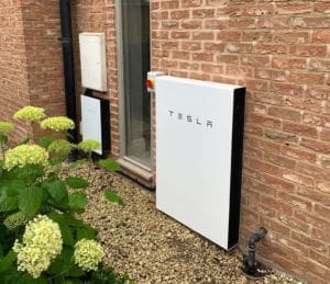 A Tesla Powerwall with a brick wall behind