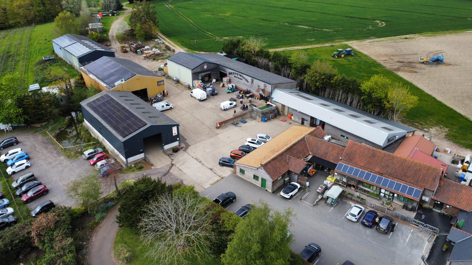An aerial shot of a farm, with solar panels on a warehouse in the bottom left corner